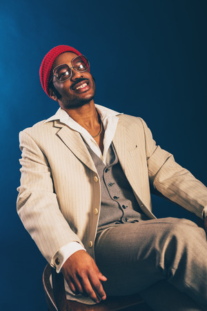 Relaxed happy Afro-American businessman sitting back in a chair looking at the camera with a beaming friendly smile of satisfactionの写真素材