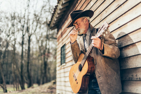 Senior Country and Western Male Musician with Guitar Instrument, Smoking a Cigarette While Leaning...