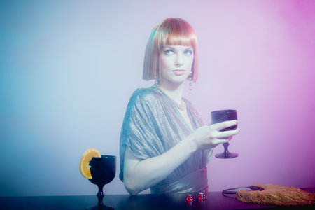 Glamorous Woman with Red Hair Wearing Shiny Retro Gown Standing at Bar Holding Wine Glass in Smoky...