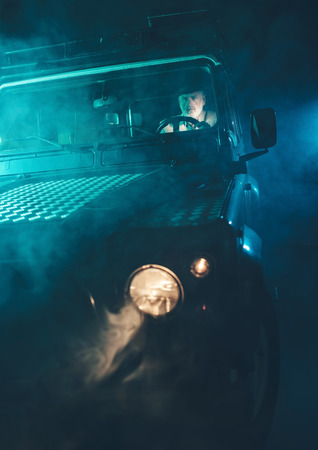 Serious Middle Aged Guy Driving his Vintage Vehicle Somewhere in the Middle of Blurry Dark Nightの写真素材