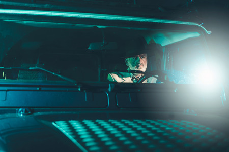 Bearded Matured Guy Wearing a Hat, Driving a 4x4 Vehicle in the Middle of the Night with Pensive Facial Expression.の写真素材