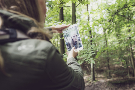 Woman in forest making selfie. Rear view.の写真素材
