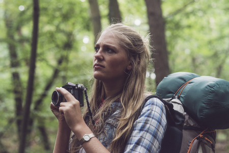 Observing woman in forest holding camera ready.の写真素材