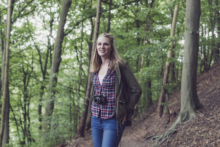 Young woman in forest holding vintage camera.の写真素材