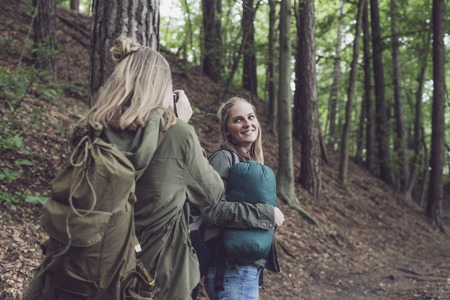 Twin sister in forest photographing each other.の写真素材