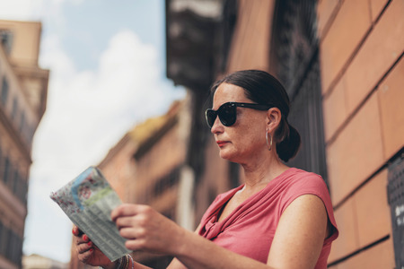 Map reading female tourist with sunglasses in Rome, Italy.の写真素材