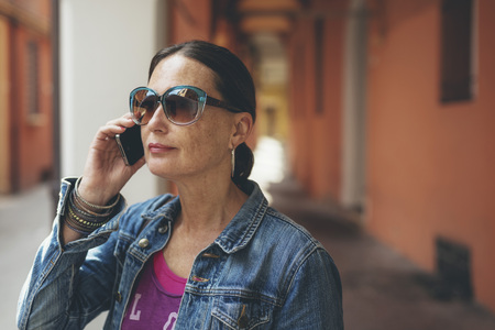 Calling woman with sunglasses at streets of Bologna, Italy.の写真素材