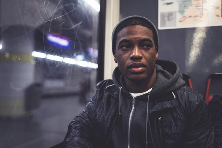 Afro man with woolen cap sitting at window from metro.の写真素材