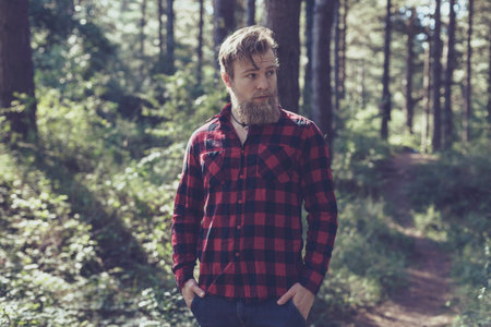 Man with beard in pine tree forest.