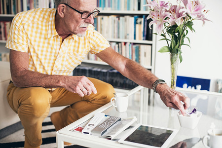 Man at table in living room picking coffee milk.の写真素材