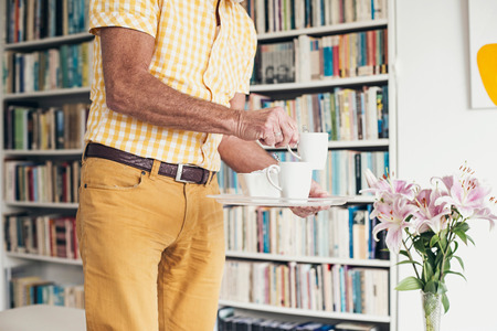 Hands of senior man holding tray with coffee.の写真素材