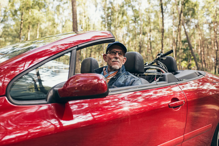 Active retired man in cabriolet car enjoying nature.の写真素材