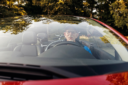 Senior man sitting in sports car outdoors in park.の写真素材