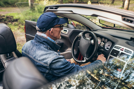 Rear view of senior man in sports car in nature.の写真素材