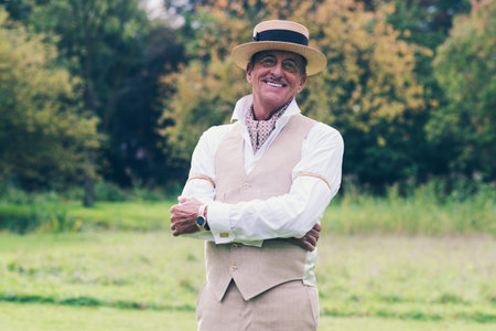 Smiling senior man in suit and hat enjoying his estate.