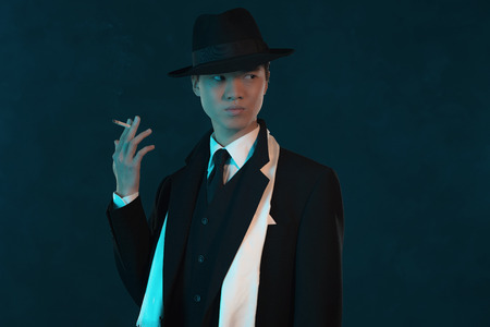 Retro 1940 asian gangster fashion man. Holding cigarette.の写真素材