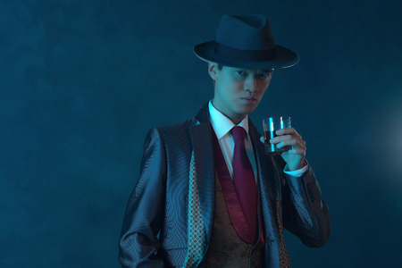 Vintage 1940 asian gangster fashion man. Holding glass of whiskey.の写真素材