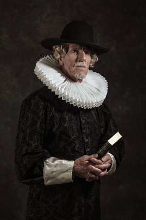 Official portrait of historical governor from the golden age. Holding a book. Studio shot against dark wall.の写真素材