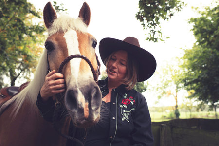 Woman in western style stroking her horse.