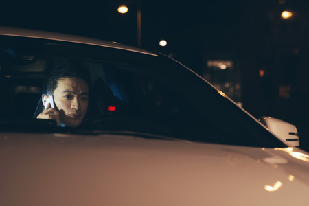 Young asian businessman calling with cellphone in car at night.の写真素材