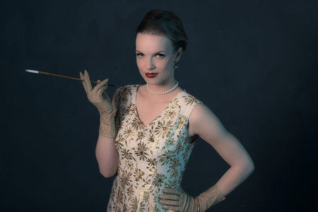 Sensual retro 1950s posh fashion woman in gold dress holding cigarette pipe.