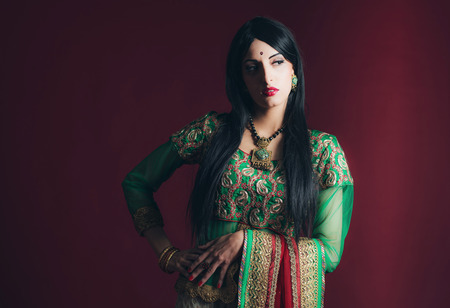 Traditional vintage Bollywood fashion girl against dark red background.の写真素材