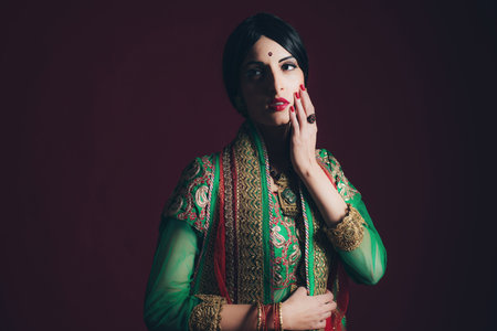 Traditional vintage Bollywood fashion girl against dark red background.