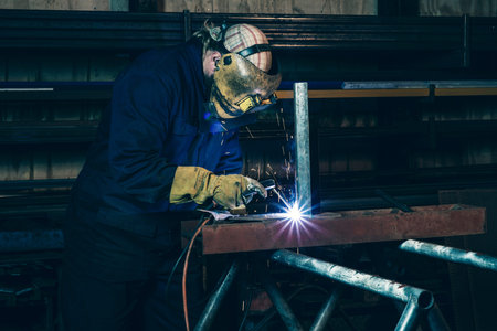 An industrial welder welding iron in workplace