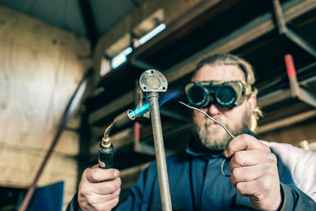 Man with goggles soldering iron pipeの写真素材