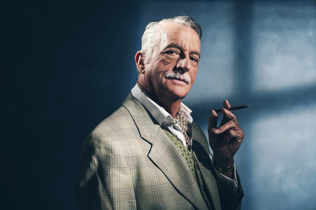 Cigar smoking retro 1940 senior businessman. Studio shot.の写真素材