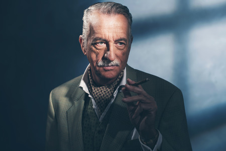 Cigar smoking retro 1940 senior businessman. Studio shot.の写真素材