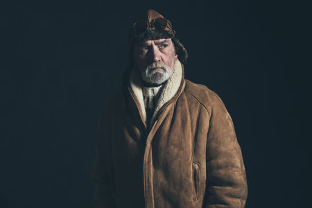 Vintage veteran aviator wearing winter coat and leather cap.