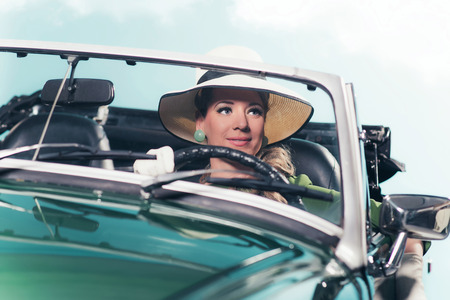 Smiling retro 60s woman with driving sports car.の写真素材