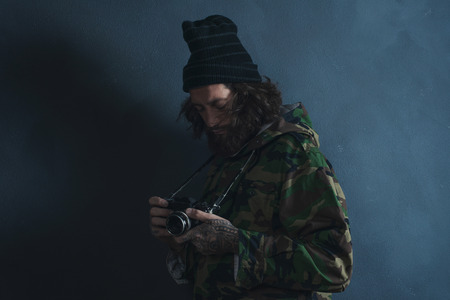 Vintage photographer with beard and long hair wearing camouflage coat.の写真素材