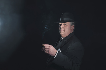 Vintage 1930s gangster holding cigar. Classic studio portrait.の写真素材