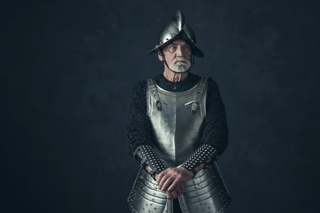 Bearded knight standing with sword in front of gray wall.の写真素材