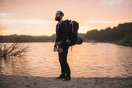 Backpacker standing at dune lake in morning sunlight