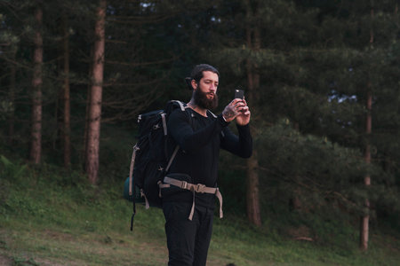 Hiker in forest photographing with smartphone