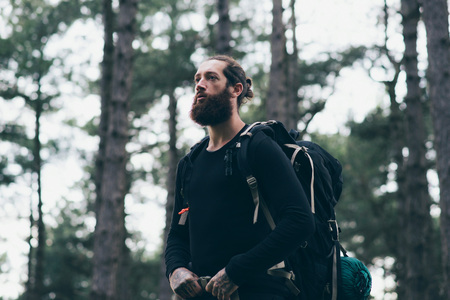 Bearded man with backpack trekking in forestの写真素材