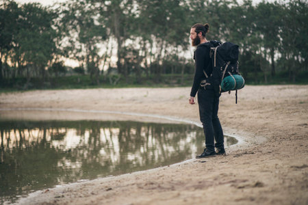 Bearded backpacker standing at lake
