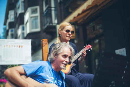 Man and woman playing guitar at outdoor cafe in summertime. Amsterdam. The Netherlands.の写真素材