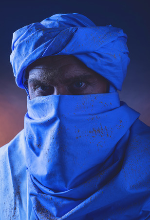 Berber man in night light wearing blue turban with white robe. Studio shot.の写真素材
