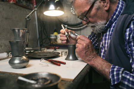 Man soldering old tin vaseの写真素材