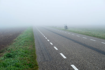 Bicycle standing aside rural road in mist. Geesteren. Achterhoek. Gelderland. The Netherlands.の写真素材