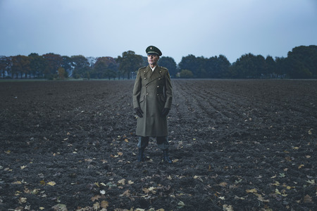 Patrolling retro 1940s military officer standing on farmland.の写真素材