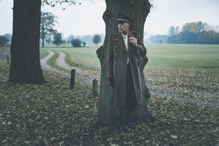 Resting retro 1940s military officer smoking cigarette under tree.の写真素材