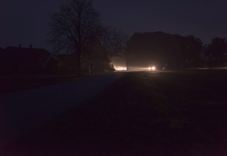 Car with headlights driving on rural road at night.の写真素材