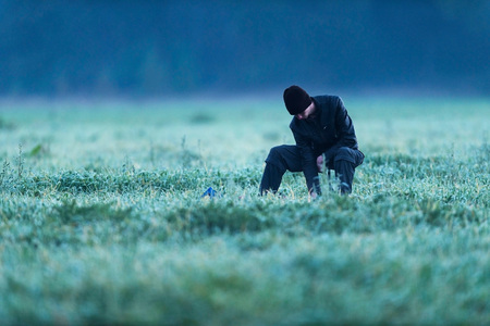 Man sitting on stool in meadow on cold morning. Noordijkerveld. Achterhoek. Gelderland. The Netherlands.の写真素材