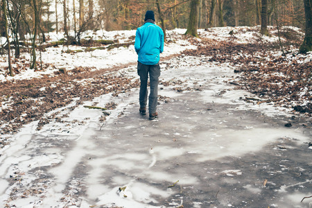 Young man standing on frozen puddle in forest.の写真素材