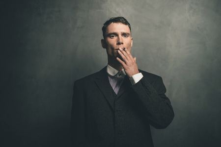 Retro 1920s english gangster in suit smoking cigarette.の写真素材